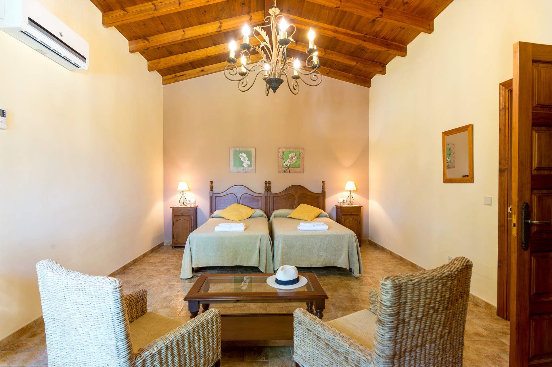 A bedroom with two beds, a chandelier, and a wooden ceiling.