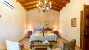 Une chambre avec deux lits, un lustre et un plafond en bois.