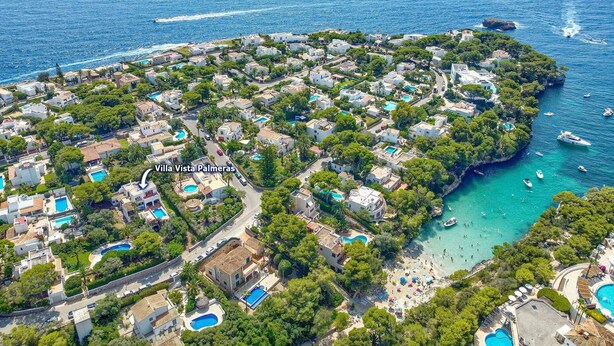 Vista aérea de Villa Vista Palmeras, mostrando una distribución costera con varias piscinas, una zona de playa y un puerto deportivo con barcos.