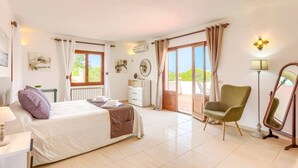 Un dormitorio con cama, una silla, una lámpara y una ventana con cortinas.