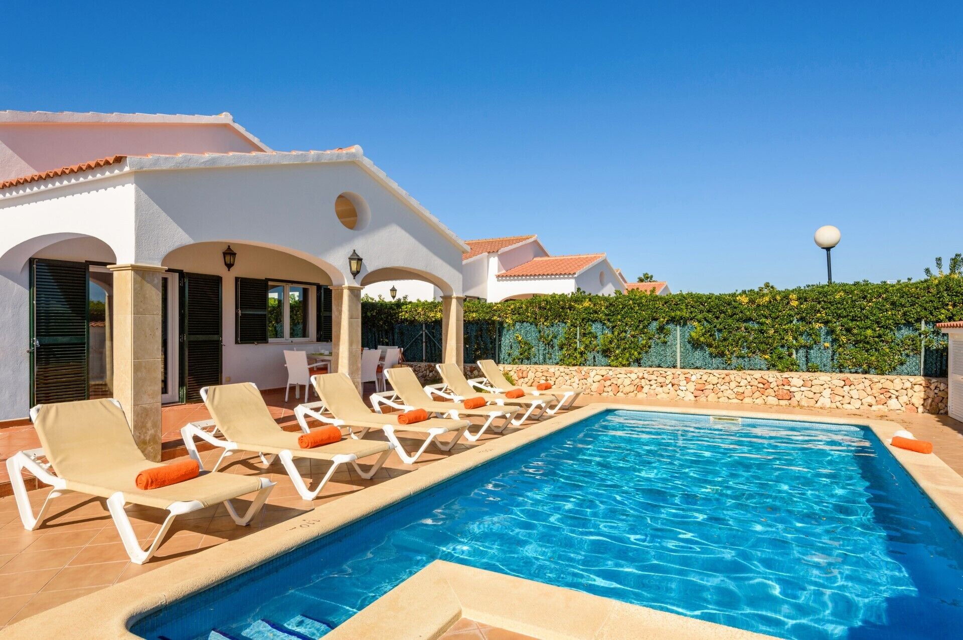 A swimming pool with lounge chairs and a covered patio area.