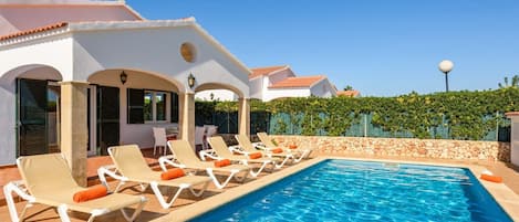 A swimming pool with lounge chairs and a covered patio area.