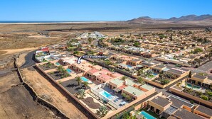 Luchtbeeld van Villa Vista Montana, met een dichtbevolkt woongebied met meerdere gebouwen, wegen en een helder uitzicht op het omliggende woestijnlandschap.