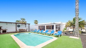 Una piscina con poltroncine blu, una zona pranzo e un edificio con ampie finestre.