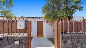 Un cancello con un muro in pietra, una porta in legno e un vialetto che conduce a un edificio.