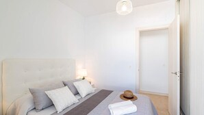 A bedroom with a bed, pillows, a blanket, a hat, and a lamp. - Villa Yucca Mar by Villa Plus (Playa Blanca)
