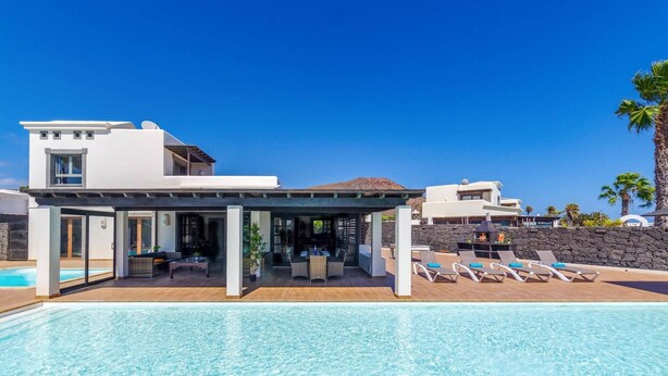 A modern resort with a pool, lounge chairs, and a covered outdoor area. - Villa Zen by Villa Plus (Montaña Roja)