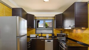 A modern kitchen with dark cabinetry, a built-in dishwasher, a microwave, and a toaster. - Villa Zen by Villa Plus (Montaña Roja)