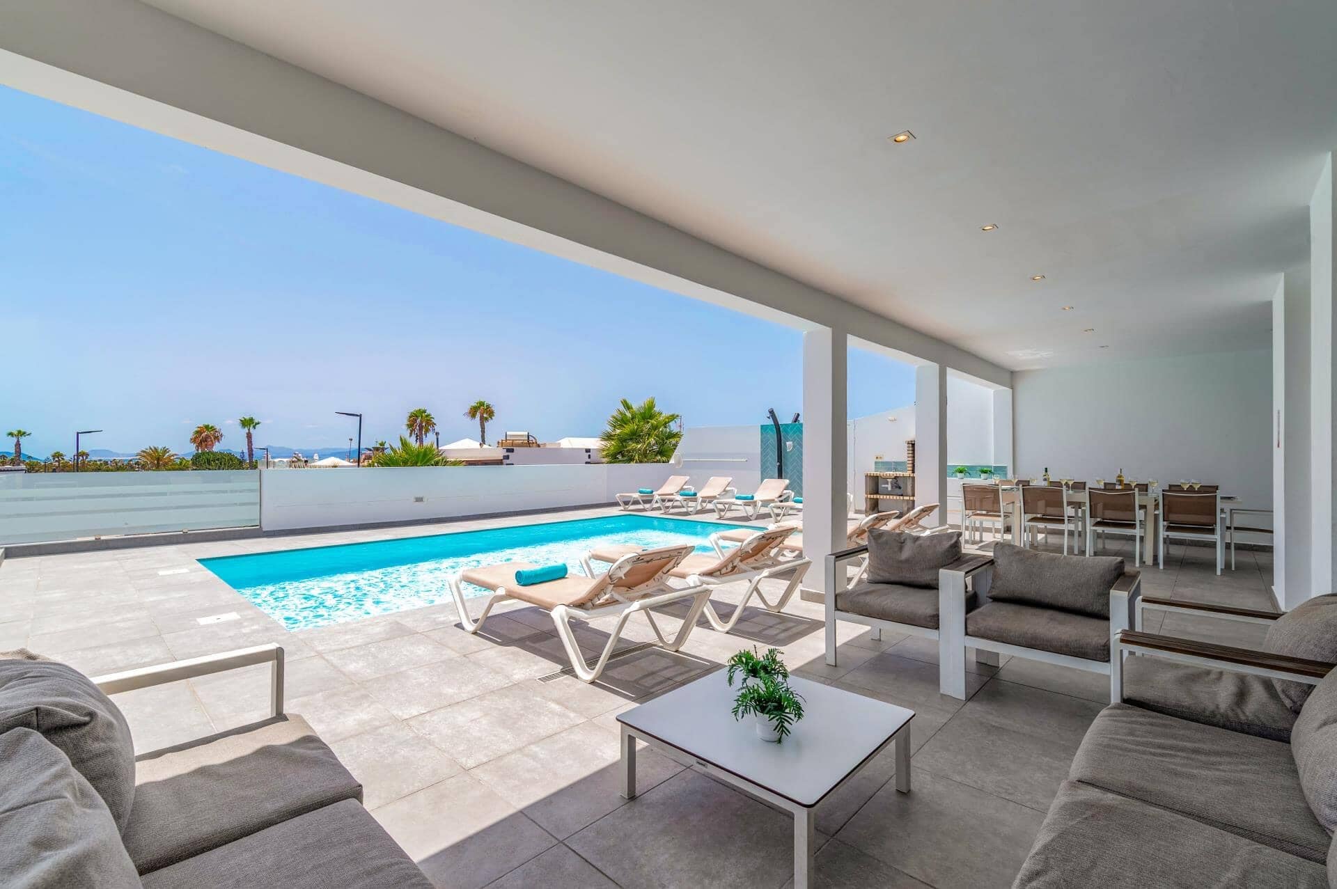 A modern outdoor pool area with lounge chairs and a dining setup.