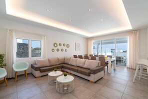 A modern living room with a sectional sofa, round coffee tables, and a dining area with a glass table.
