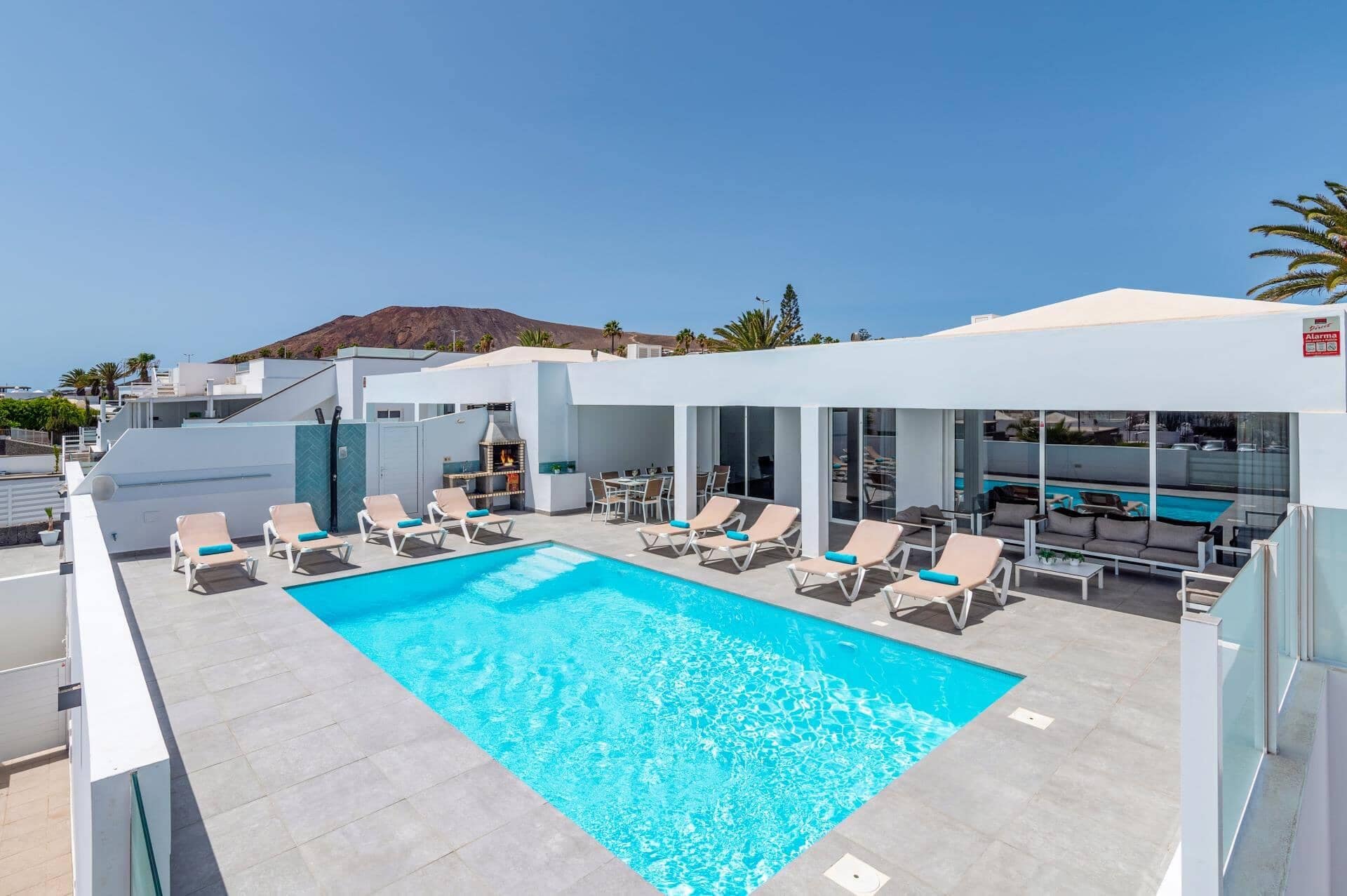 Zona de piscina en la azotea con sillones de descanso y una parrilla.