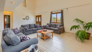 A spacious living room with two grey sofas, a wooden coffee table, and a potted plant.