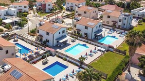 A coastal residential area with multiple white buildings, a swimming pool, and a view of the sea.