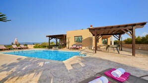 A pool area with lounge chairs and a building with a pergola. - Villa Andriana by Villa Plus (Latchi)