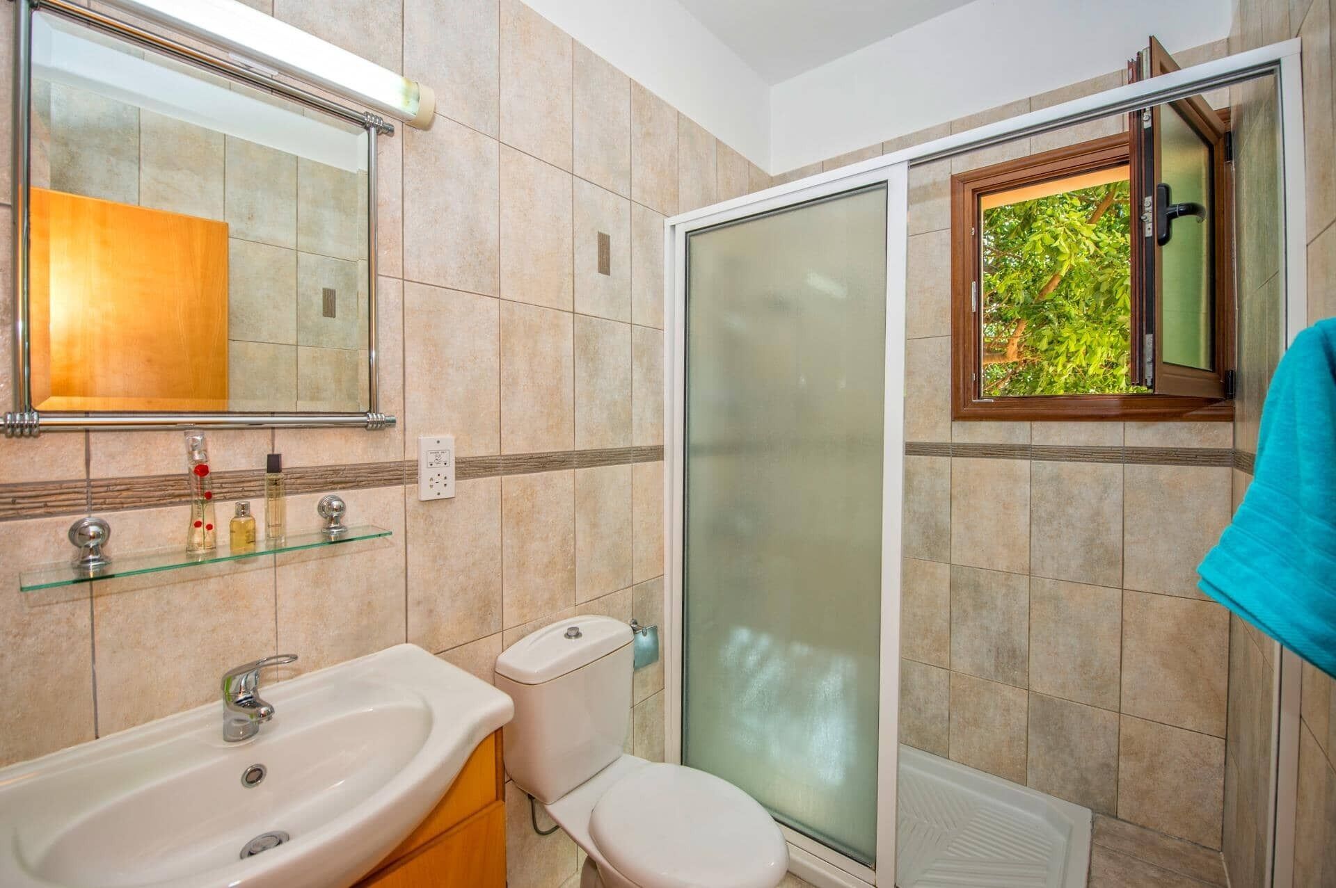 Un baño con cabina de ducha de vidrio, lavamanos, inodoro y espejo.