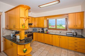 Una cocina con armarios de madera, estufa, microondas y ventana con vista a vegetación.
