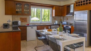 Una cocina moderna con armarios de madera, microondas integrado, refrigerador Bosch y un comedor con una mesa lista para cuatro.