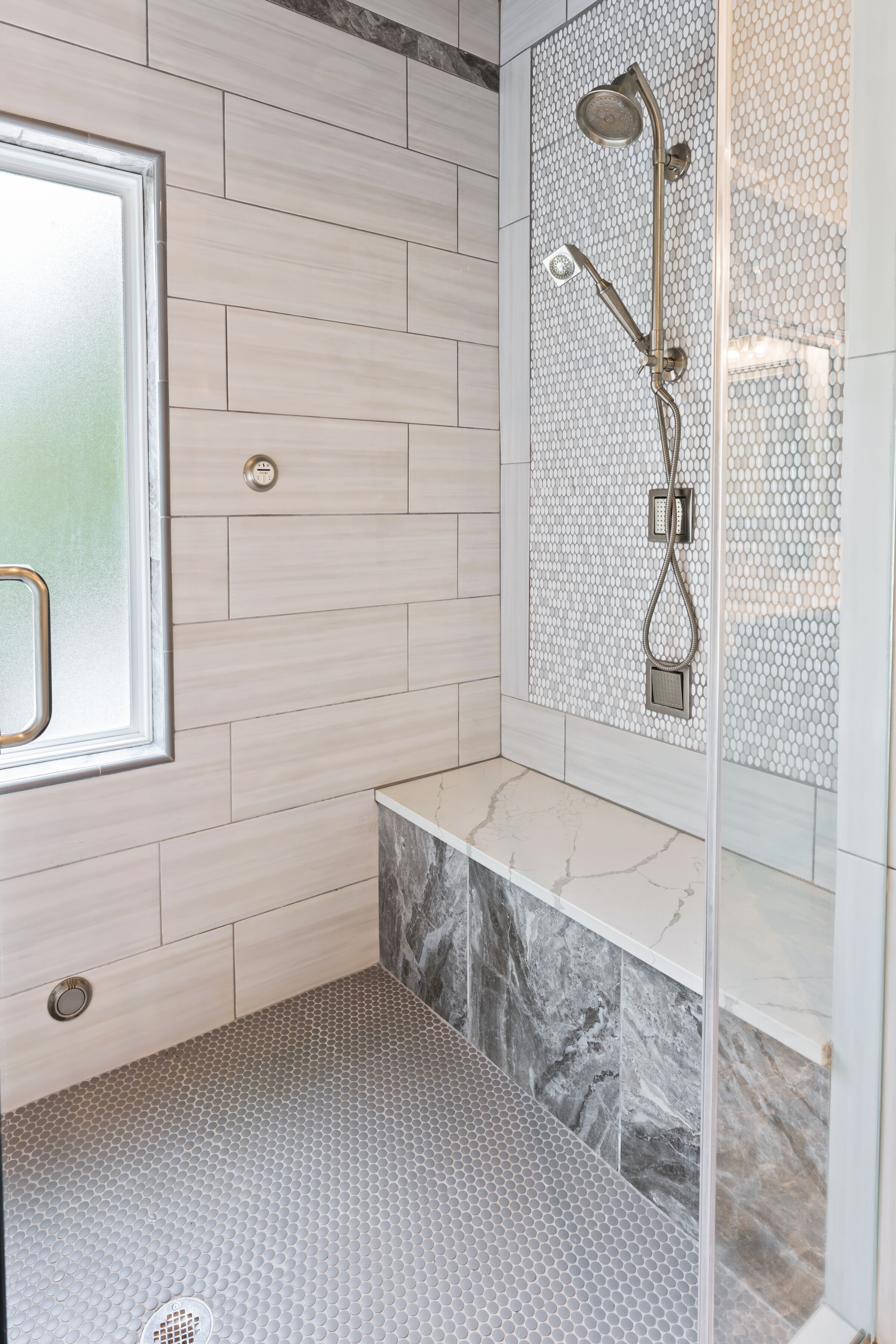 Un baño moderno con ducha, una ventana y suelo de baldosas de mármol.