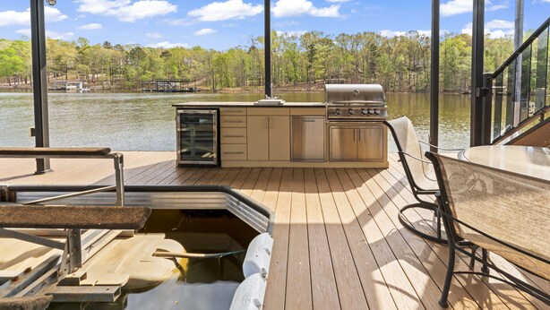 Una terraza con una parrilla, asientos y vistas al lago.