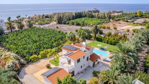 Une villa blanche avec un toit recouvert de tuiles rouges, des panneaux solaires, une piscine et une vue sur la mer.