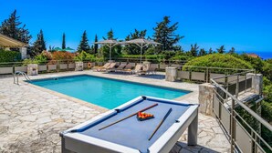 Un espace piscine comprenant une table de billard et des chaises longues.