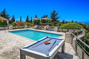 Area piscina con tavolo da biliardo e poltrona relax.