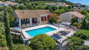 Une villa dotée d’une piscine, de murs en pierre et offrant une vue sur les collines environnantes.