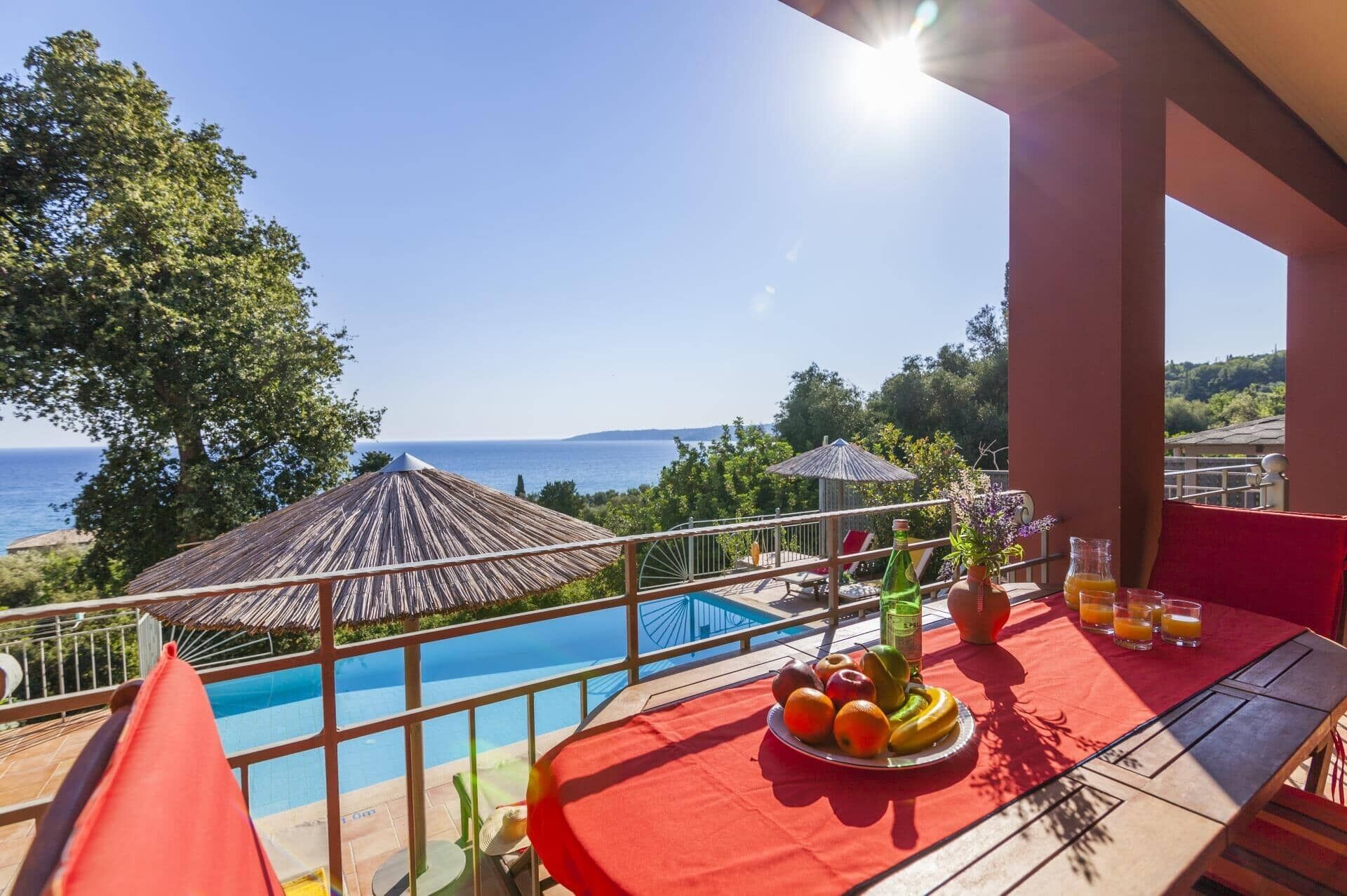 Un balcó amb piscina, taula amb fruita i begudes, i vista al mar.