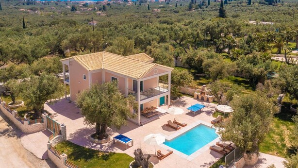 Eine zweigeschossige Villa mit Swimmingpool, umgeben von Grün und mit Blick auf die Küste.