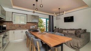 Eine moderne Küche mit Esstisch und Stühlen aus Holz, einem eingebauten Backofen und einem großen Fenster.