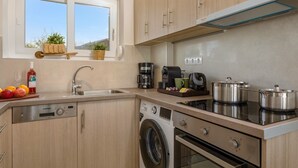 Una cuina moderna amb armaris de fusta, un rentaplats integrat, una rentadora, una placa de cocció i una cafetera.