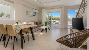 Un saló modern amb zona de menjador, sofà, televisió i vistes a la zona de la piscina exterior.