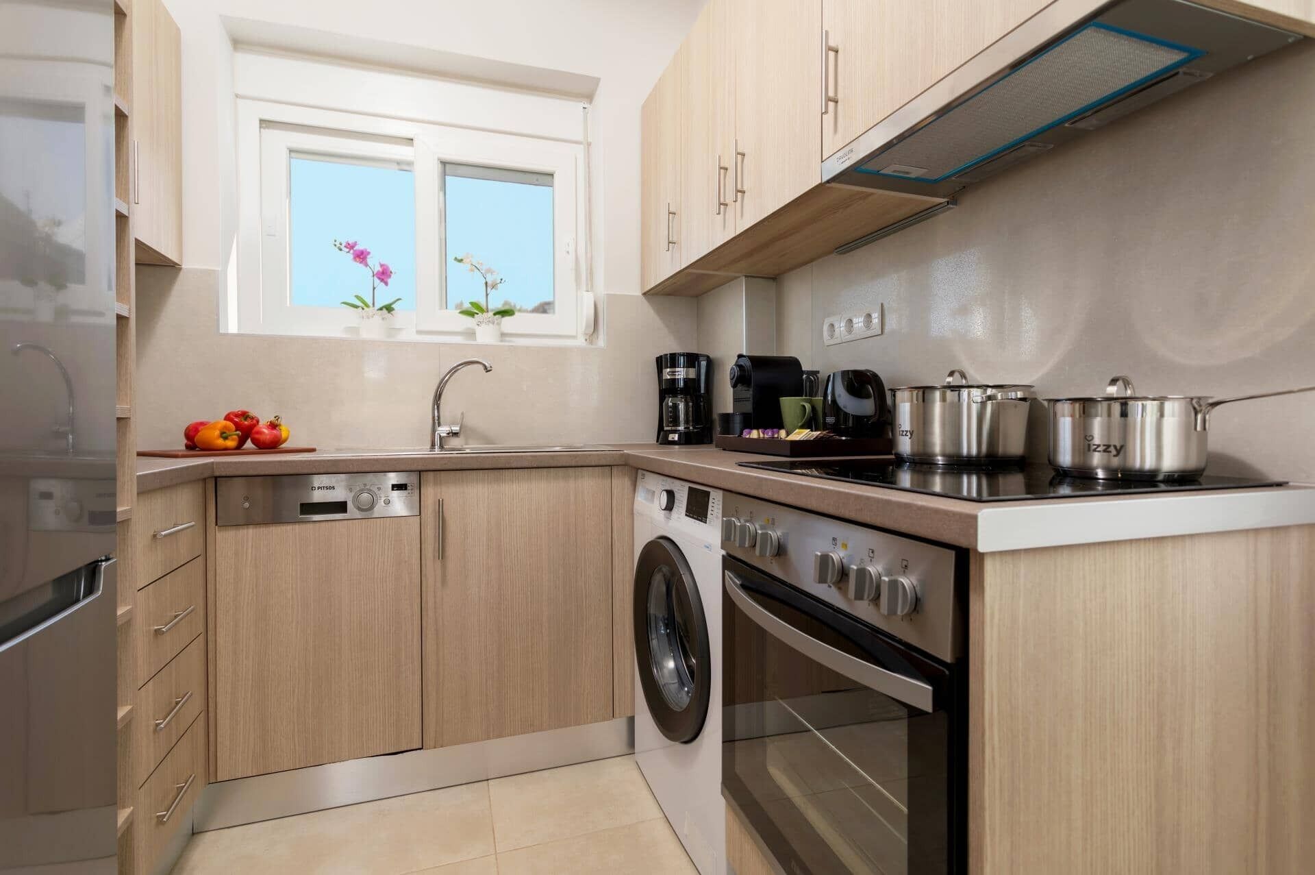 A compact kitchen with a washing machine, a coffee maker, and a stove.