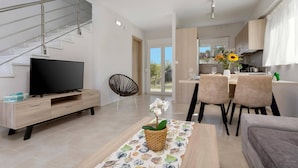 A modern living room with a TV, sofa, and dining area with chairs and a table. - Villa Vilenia Horizon by Villa Plus (Katastari)