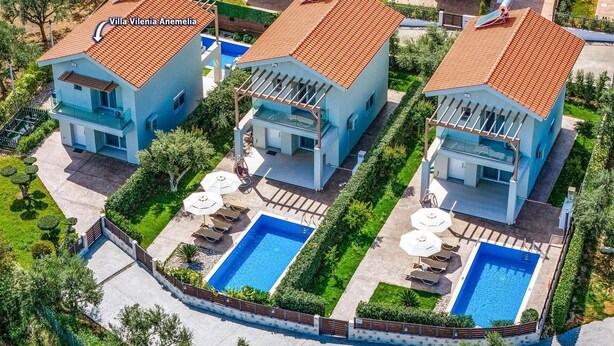 Una villa moderna con techo de tejas, piscina y un jardín bien cuidado.