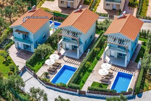 A modern villa with a tiled roof, a swimming pool, and a well-maintained garden.