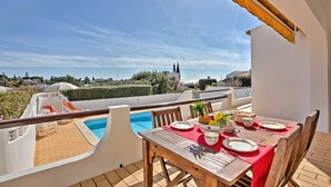 A terrace with a pool, dining table set with plates and cutlery, and a view of the surrounding landscape. - Villa Africa by Villa Plus (Praia do Carvoeiro)