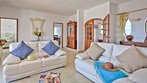 A spacious living room with two white sofas, a wooden cabinet, and a large mirror. - Villa Africa by Villa Plus (Praia do Carvoeiro)