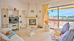 A living room with a fireplace, a glass coffee table, and a view of the outdoors. - Villa Africa by Villa Plus (Praia do Carvoeiro)