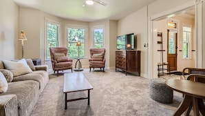 Un salon comprenant un canapé, des fauteuils, une table basse, un téléviseur et un ventilateur de plafond.