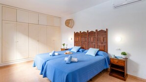 A bedroom with a large wardrobe, a wooden headboard, and a bedside table with a plant.