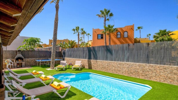 A pool area with lounge chairs and a barbecue grill.