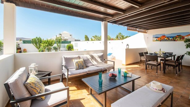 En takterrass med en soffa, ett matbord och stolar, med utsikt över stadsbilden.