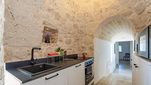 Eine Küche mit Steinwand, Spüle, Herd und Fenster.
