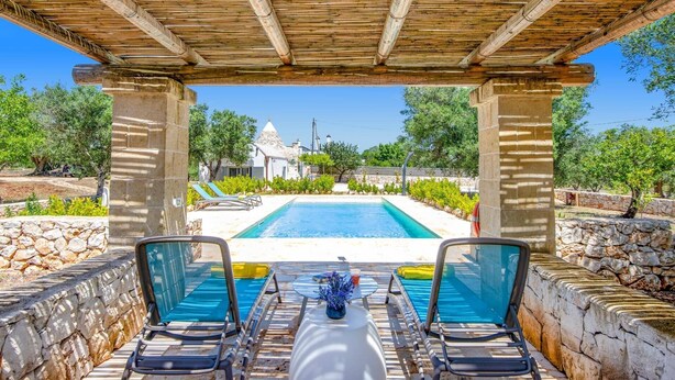 Ein Poolbereich mit Steinmauern und einer Pergola darüber.