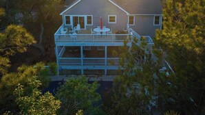 A two-story house with a balcony, surrounded by trees.