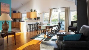 A spacious living area with a dining table, chairs, a sofa, and a kitchen in the background.