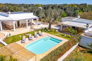 Une villa avec piscine, un espace salon extérieur et un jardin.