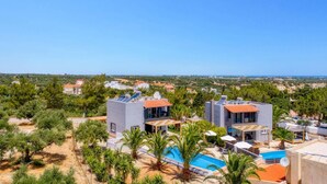 A modern resort with two buildings, a pool, and a view of the sea. - Villa Alpha by Villa Plus (Hersonissos)