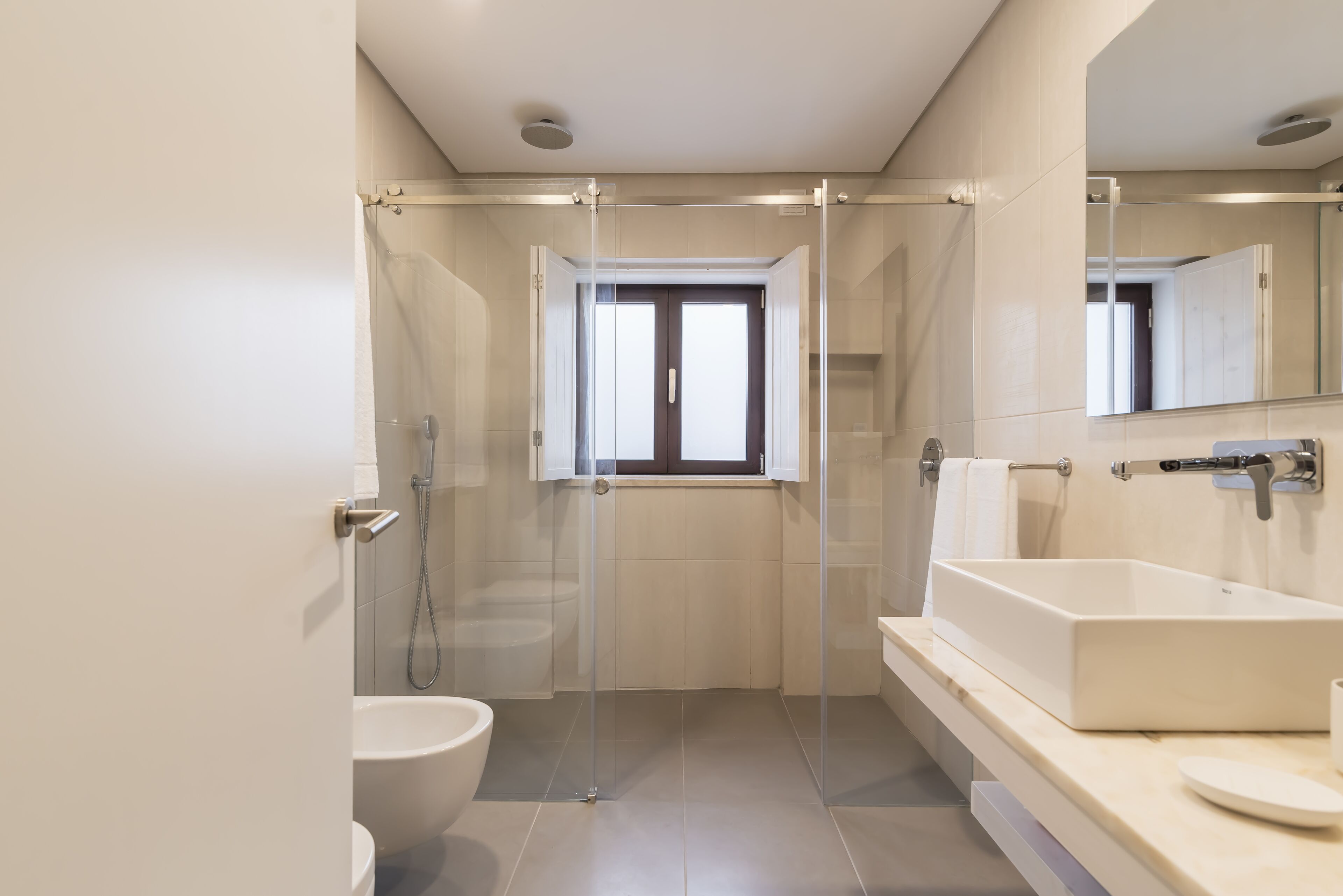A modern bathroom with a glass shower enclosure, a large sink, and a toilet.